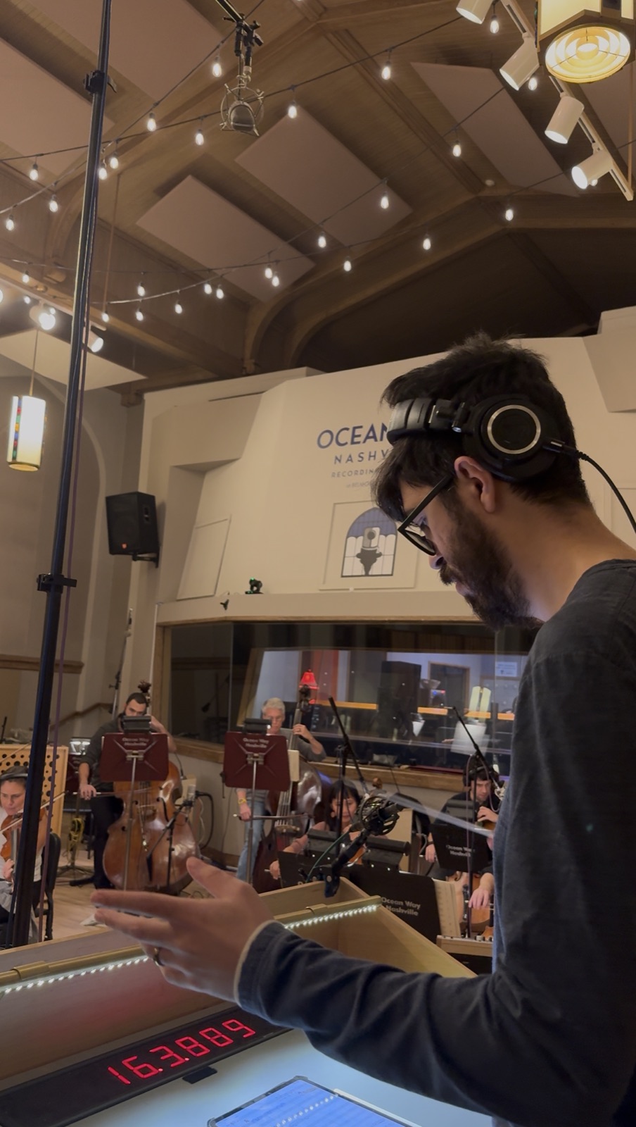 Felipe Paccagnella conducting a string section with headphones on